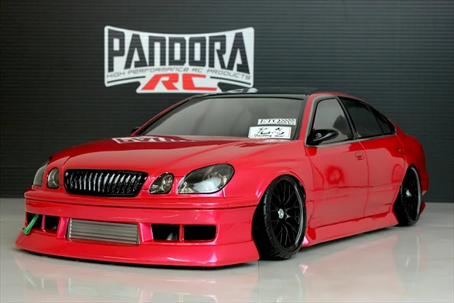 Red RC drift car body shell styled as a Toyota Aristo JZS161 on a reflective surface with a Pandora RC backdrop.