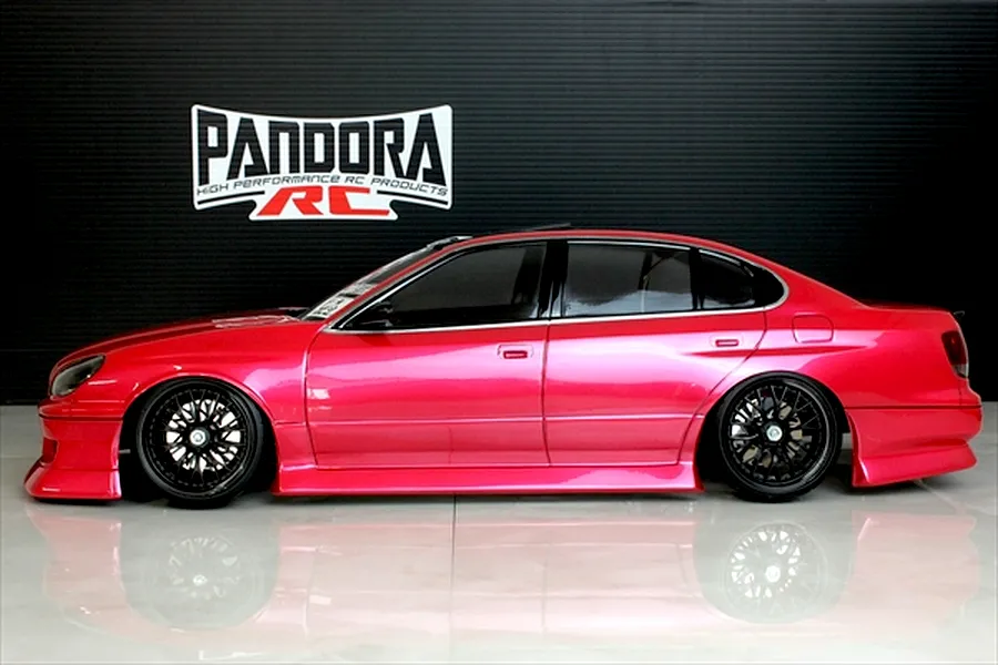 Side profile of a painted red RC drift car body shell on a gloss floor with Pandora RC logo in the background.