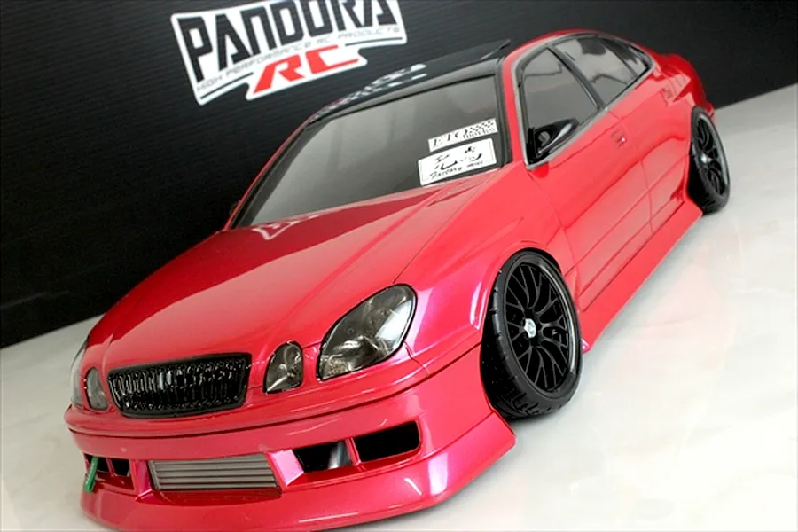 A painted red Toyota Aristo JZS161 RC drift car body with black wheels and Pandora RC branding in the background.