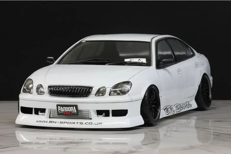 Front three-quarter view of a white Toyota Aristo RC drift car body shell with BN Sports styling on a reflective surface.