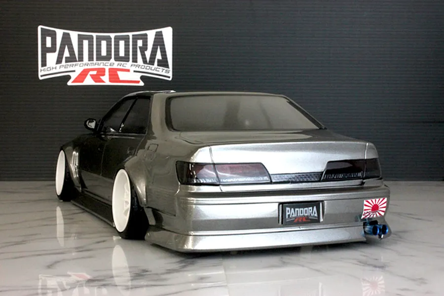 Rear three-quarter view of a painted grey RC drift car body with white deep dish wheels and Pandora RC branding against a dark backdrop.