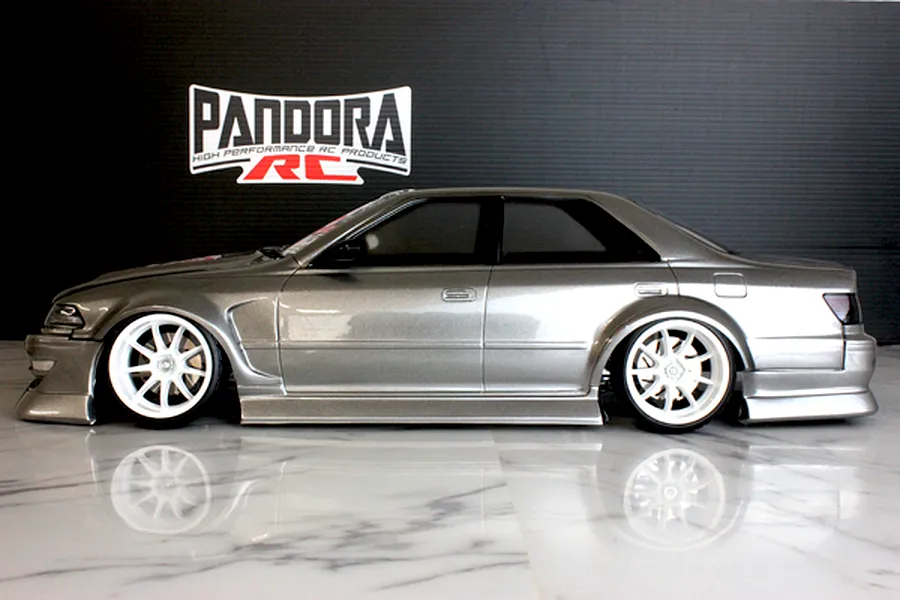 Side profile of a silver RC drift car body shell with white wheels displayed on a glossy marble surface.