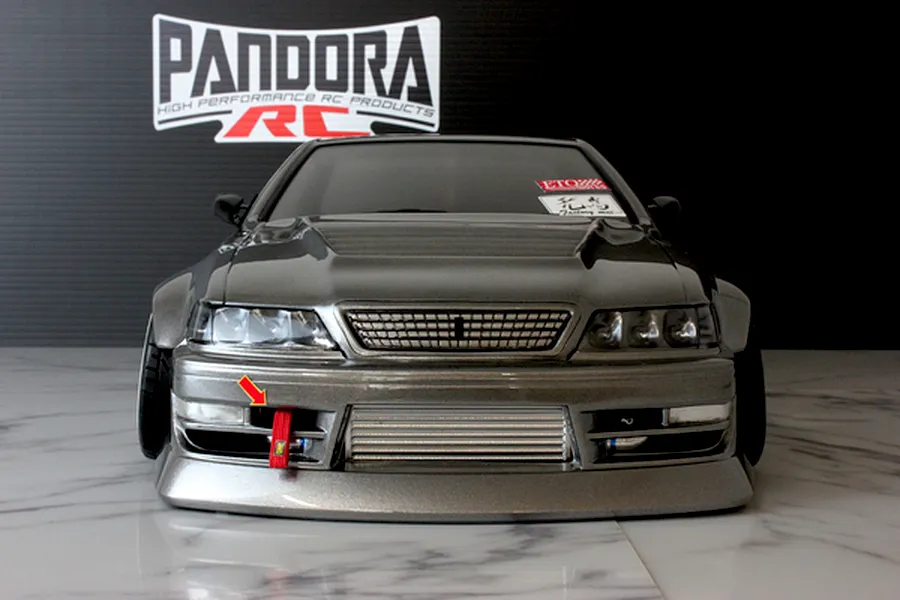 Front view of a dark grey Pandora RC Toyota Mark 2 body shell with a front mount intercooler and red tow strap on a marble surface.
