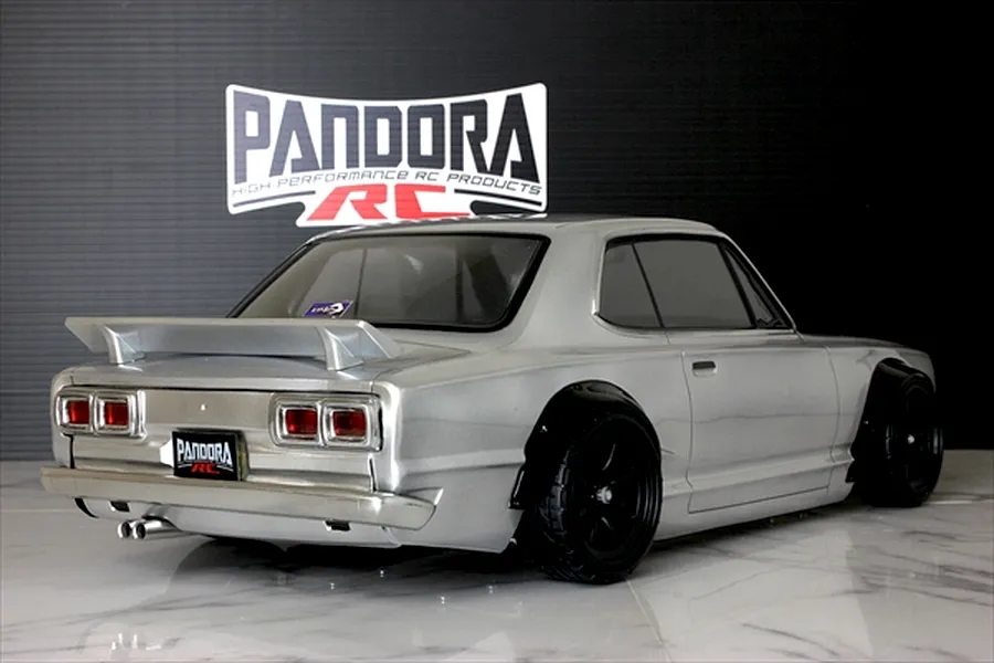 Rear three-quarter view of a silver Pandora RC KPGC10 Skyline GT-R drift car body with black wheel arches and wheels on a glossy white surface.