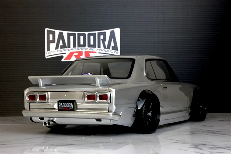 Rear three-quarter view of a silver Pandora RC KPGC10 Skyline GT-R body shell mounted on an RC chassis with a Pandora RC logo in the background.
