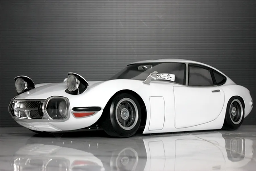 Painted white Toyota 2000GT RC drift and touring body shell mounted on a chassis with pop-up headlights.
