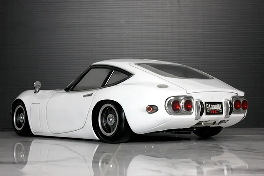 Rear three-quarter view of a white Pandora RC Toyota 2000GT RC drift car body on a reflective surface.