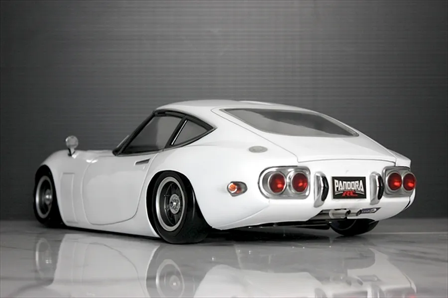Rear three-quarter view of a white Pandora RC Toyota 2000GT body shell on a reflective surface.