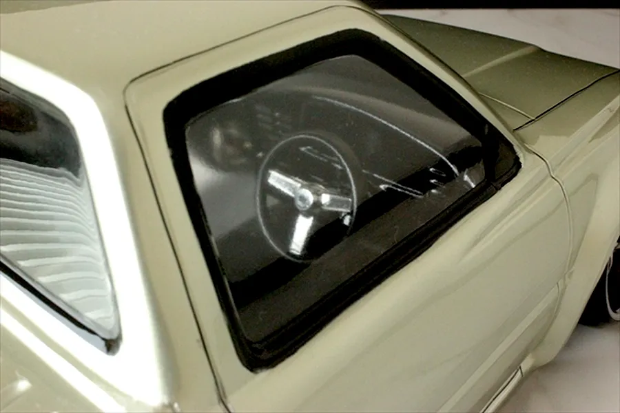 Close-up view of the interior cabin and steering wheel through the driver side window of a silver Toyota Hilux RN80 RC body shell.