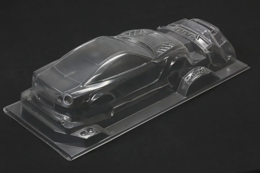 Unpainted clear polycarbonate RC car body shell for an R35 GT-R with additional parts on a black background.