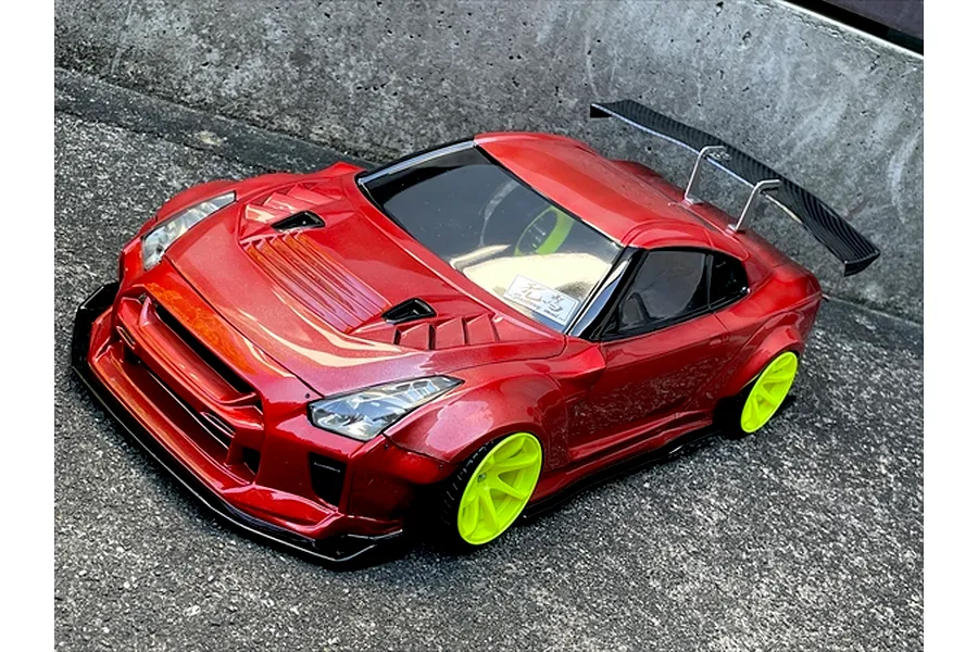 Red RC drift car body styled as a Nissan GT-R with bright green wheels and a rear wing on a concrete surface.