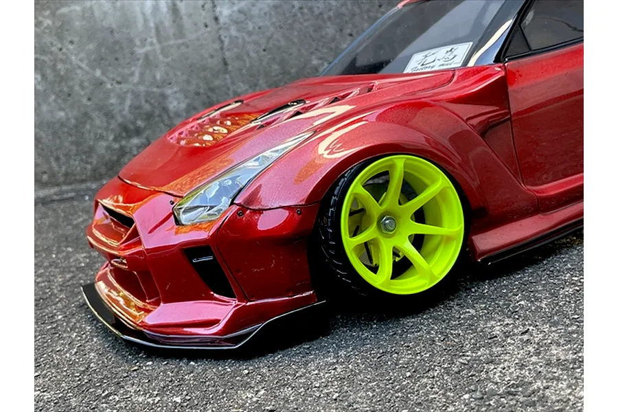 Close-up of a metallic red RC drift car body shell with wide fenders and bright yellow wheels.