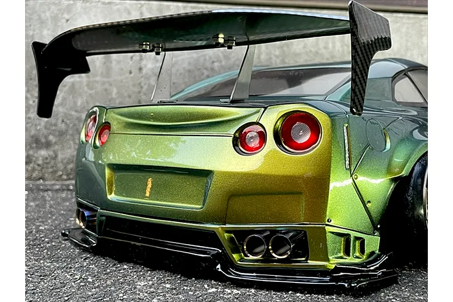 Rear view of an RC drift car body styled like a Nissan R35 GT-R with a color-shifting green and gold paint finish, large rear wing, and detailed exhaust tips.