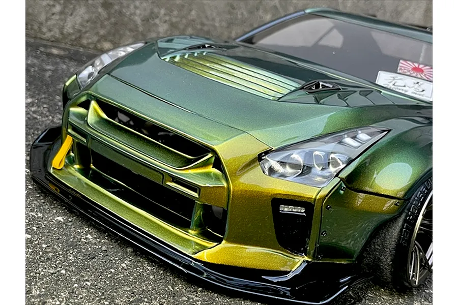 Close-up front angle of a custom painted metallic green and gold Nissan GT-R RC drift car body shell sitting outdoors.