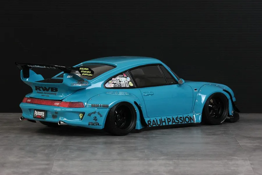Rear three-quarter view of a light blue Pandora RC RWB 993 body shell with wide fenders, black wheels, and custom sponsor decals.