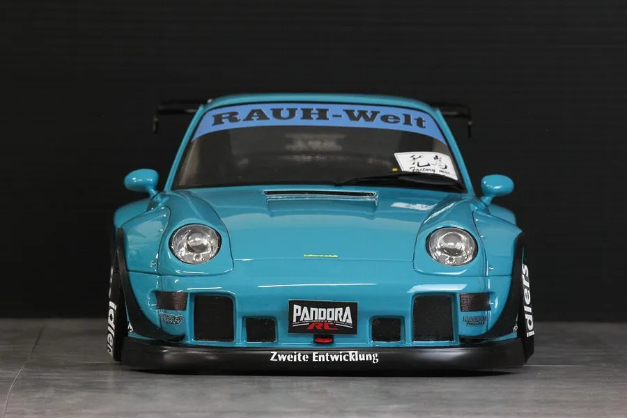 Front view of a blue Pandora RC RWB 993 type body shell with wide fenders and decals on a dark background.