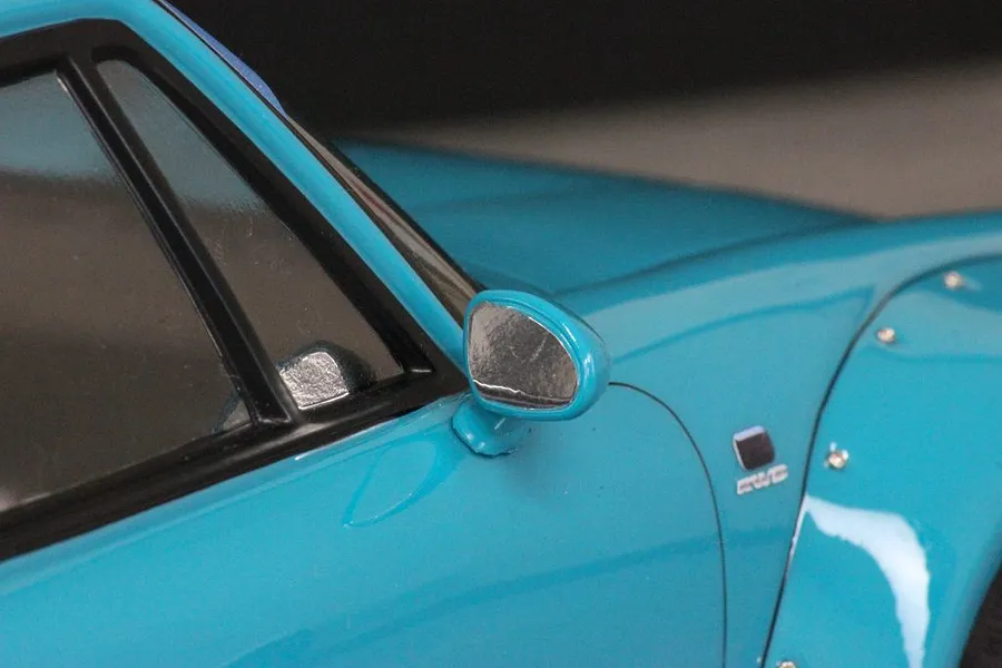 Close-up view of a blue RC car body shell showing the side mirror, window frame, and fender flare.