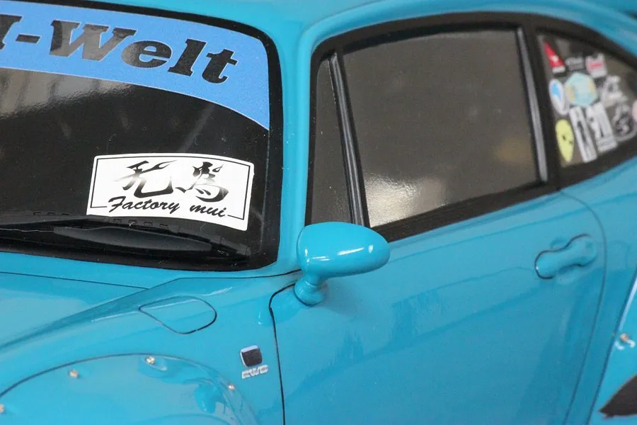 Close-up of the front side window, door mirror, and decals on a light blue Pandora RC RWB 993 body shell.