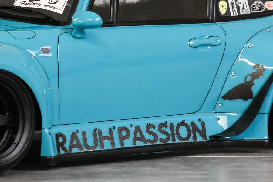 Close-up of the side profile of a light blue RC car body shell featuring black decals including RAUH-PASSION lettering.