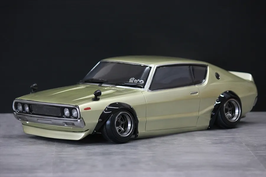 Painted light gold Nissan Skyline 2000GT-R Kenmeri RC body shell on a studio table.