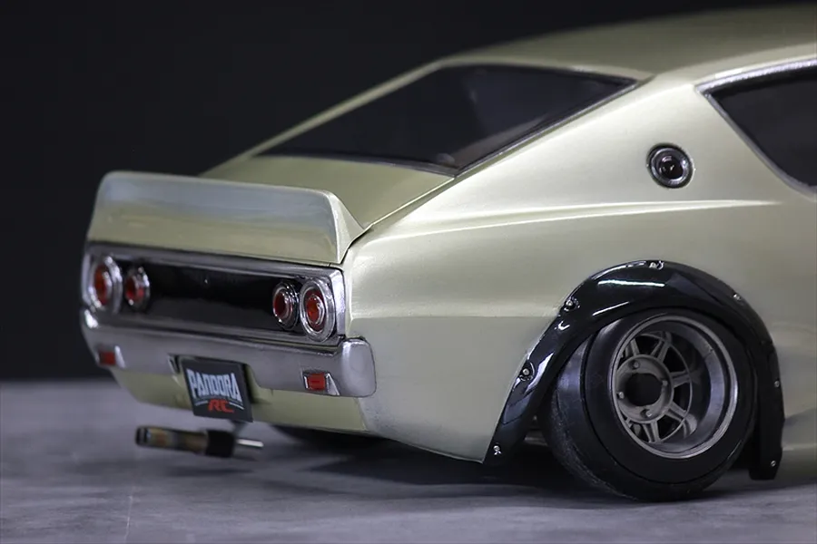Close-up rear angled view of a custom silver RC drift car body shell showing wheel arches, tail lights, and exhaust.