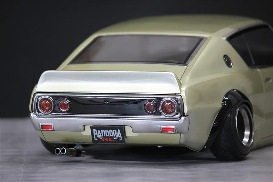 Close-up rear view of a gold Pandora RC KPGC110 Skyline 2000GT-R drift car body shell showing dual exhaust and tail lights.