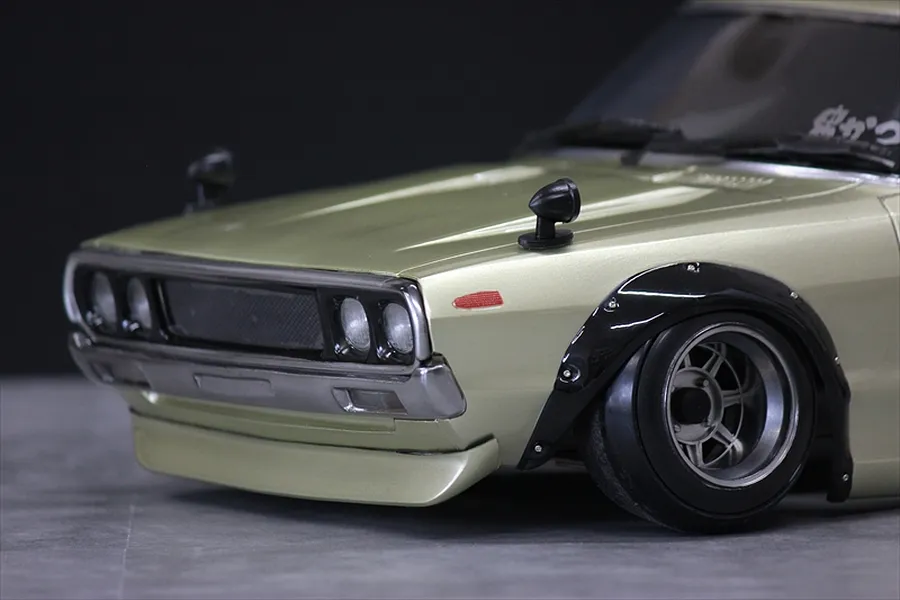 Close-up of the front quarter and fender of a metallic gold KPGC110 Skyline 2000GT-R RC car body shell.