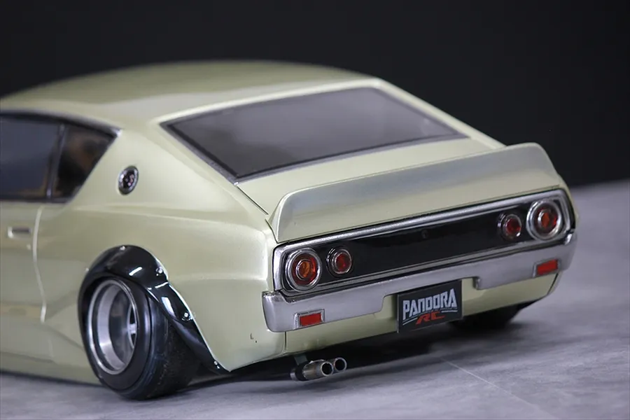 Close-up rear angled view of a custom painted RC car body resembling a classic Nissan Skyline Kenmeri with a Pandora RC license plate.