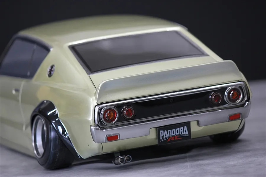 Rear three-quarter view of a painted Pandora RC KPGC110 Skyline 2000GT-R Kenmeri RC drift car body shell in metallic light gold with black fender flares.