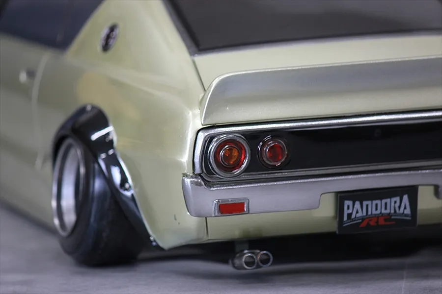 Close-up of the rear section of a light green RC drift car body showing tail lights, bumper, exhaust, and a Pandora RC license plate.