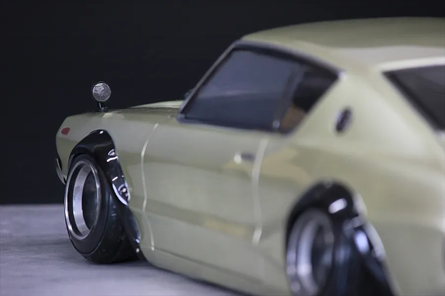 Close-up side profile of a silver RC drift car body shell showing front fender flare, side mirror, and deep dish wheels.