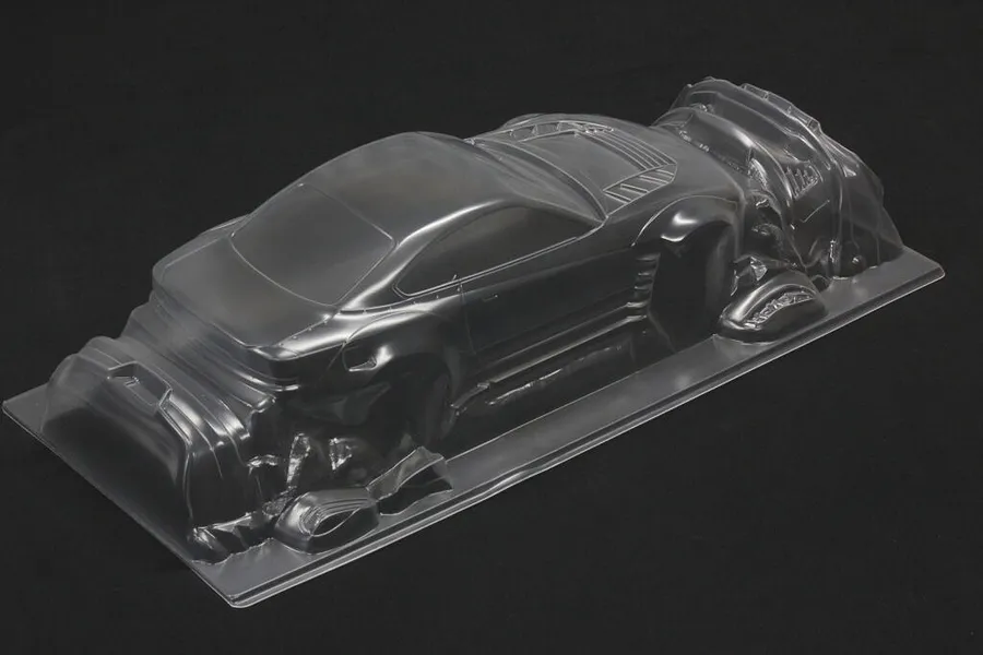 Unpainted clear polycarbonate RC drift car body shell viewed from a rear three-quarter angle against a dark background.