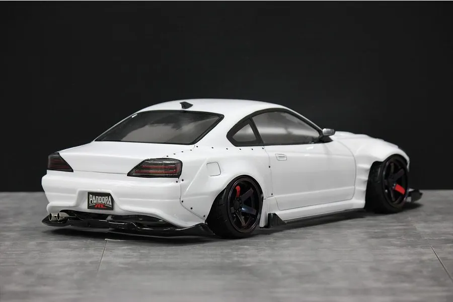 Rear-three-quarter view of a white RC drift car body styled as a Nissan S15 Silvia on a grey surface.