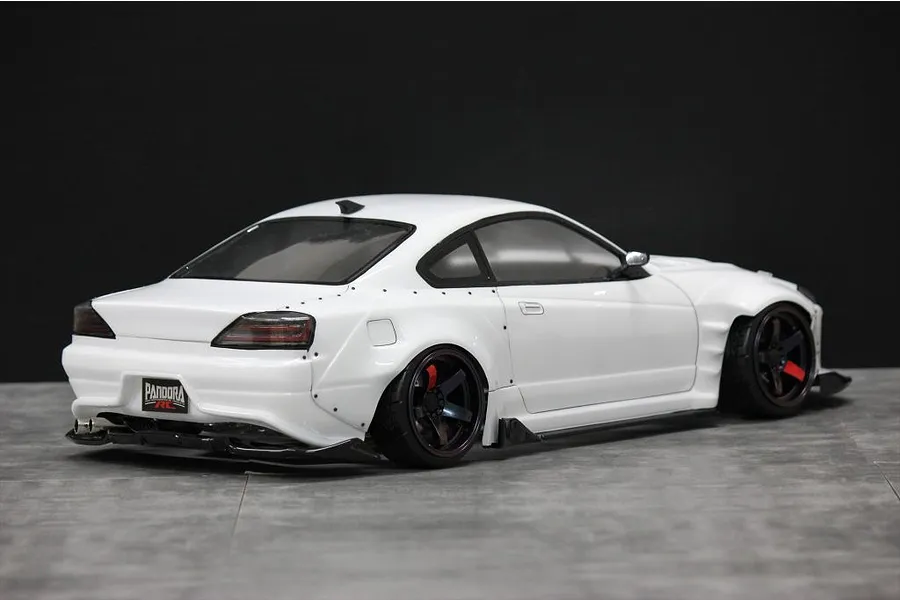 Rear-three-quarter view of a white RC drift car body shell mounted on a chassis, featuring wide fender flares and a Pandora RC license plate.
