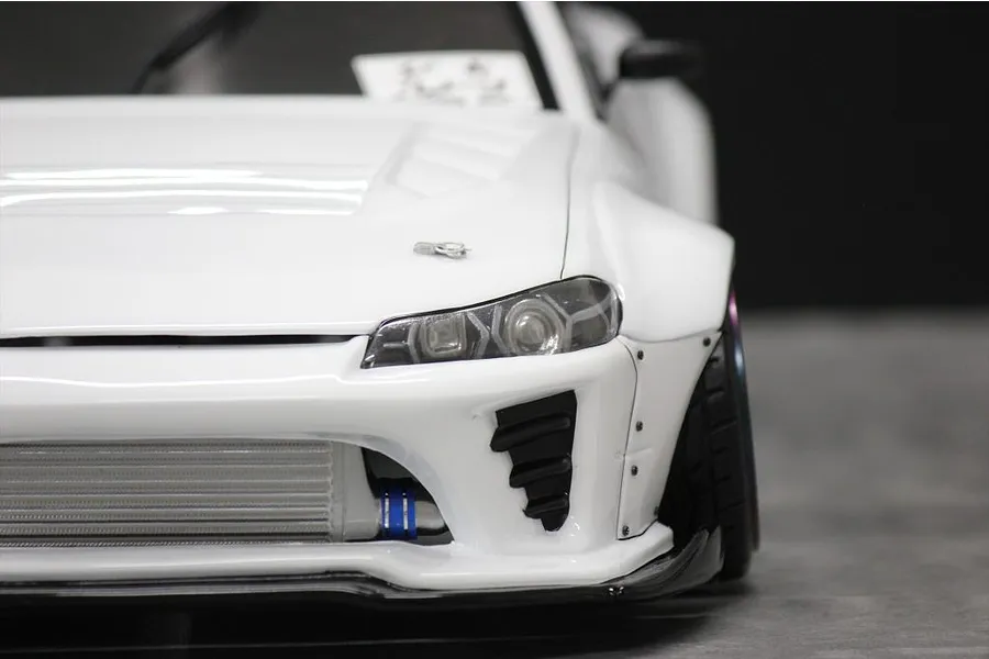 Front-quarter close-up view of a white RC drift car body shell showing detailed headlights, front bumper, and intercooler.
