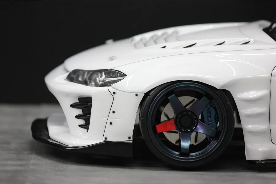 Close-up front quarter view of a white RC drift car body shell showing the front wheel, fender, and bumper details.