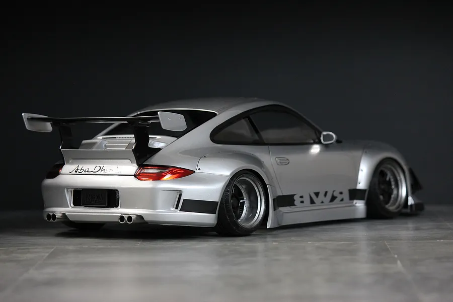 Rear-three-quarter view of a silver Pandora RC RWB 997 body shell featuring a large rear wing, wide fenders, and RWB decals.