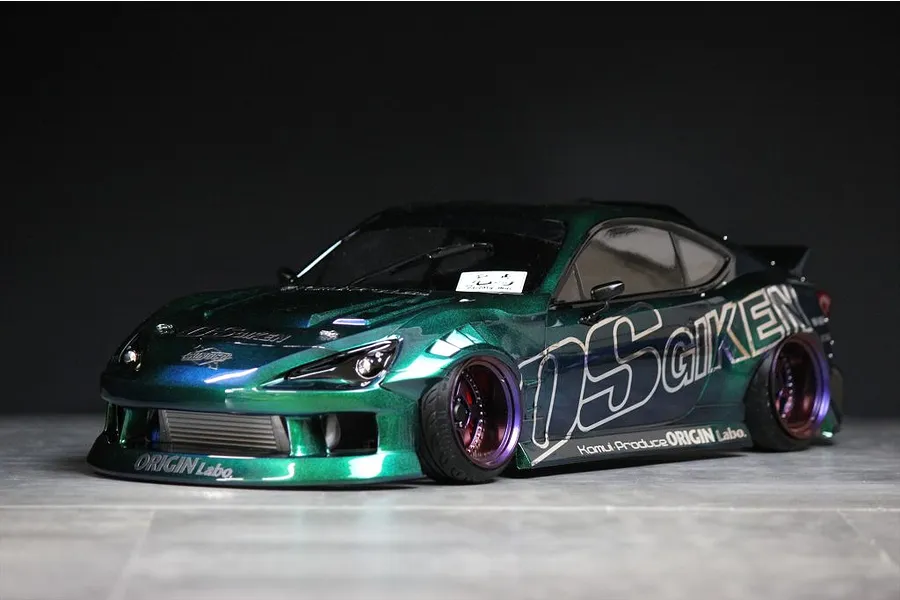 Custom painted green and blue RC drift car body shell mounted on a chassis with deep dish wheels.