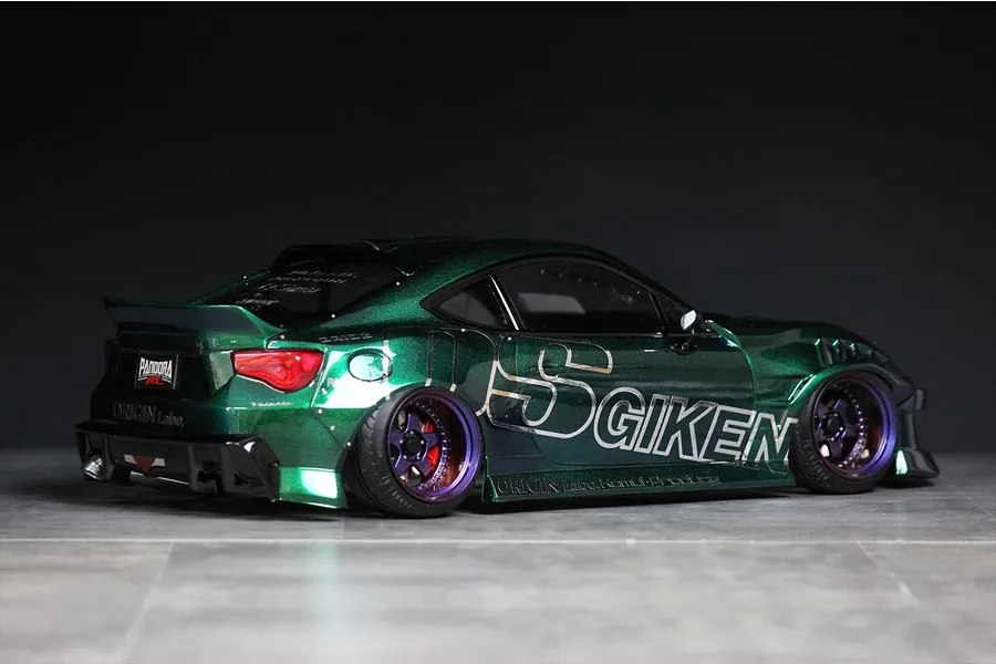 Custom painted green RC drift car body modeled after a Toyota 86 with Origin Labo decals, shown on a grey surface.