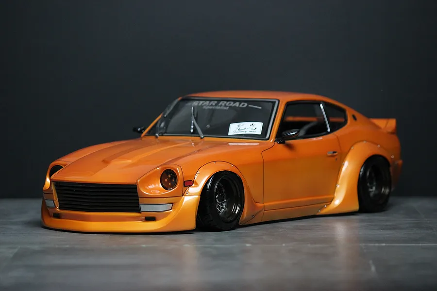 Orange Pandora RC S30 Fairlady Z Star Road drift body shell mounted on a chassis with deep-dish wheels against a dark background.