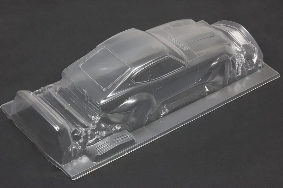 Unpainted clear polycarbonate RC car body shell of a vintage sports car shown from a rear three-quarter angle on a dark surface.