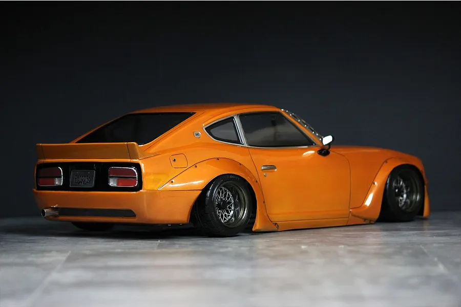 Rear three-quarter view of a painted orange Pandora RC S30 Fairlady Z body shell mounted on a chassis.