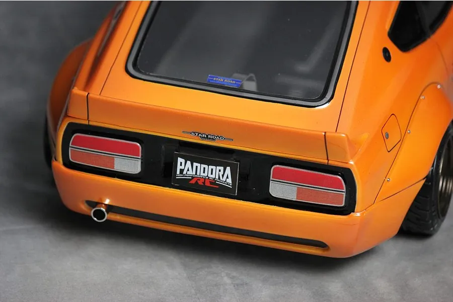 Close-up rear view of the Pandora RC S30 Fairlady Z Star Road body shell in metallic orange with realistic tail lights, exhaust, and decals.