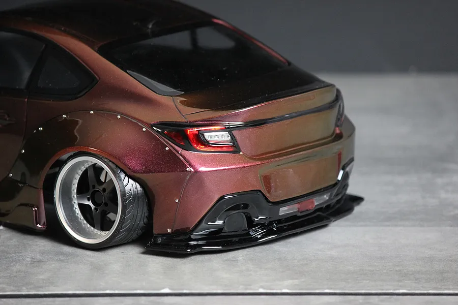 Rear three-quarter close-up of a custom painted RC drift car body showing wide rear fenders, custom wheels, and bumper detail.