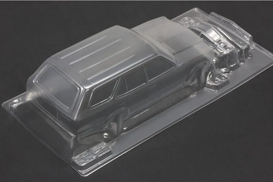 Unpainted clear polycarbonate RC sports wagon body shell shown at an angle on a dark surface.