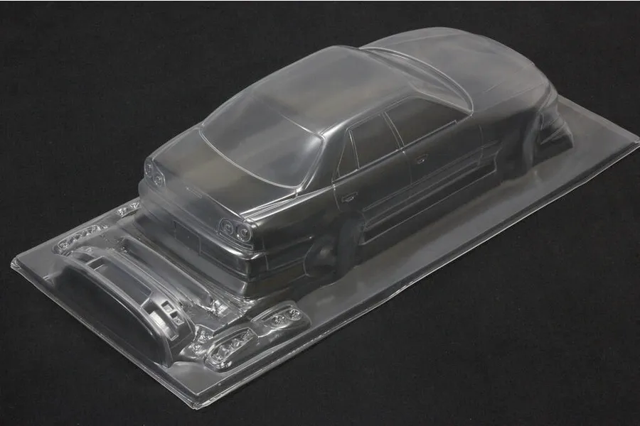 Unpainted clear polycarbonate RC drift car body shell with separate parts molded on a sheet against a dark background.