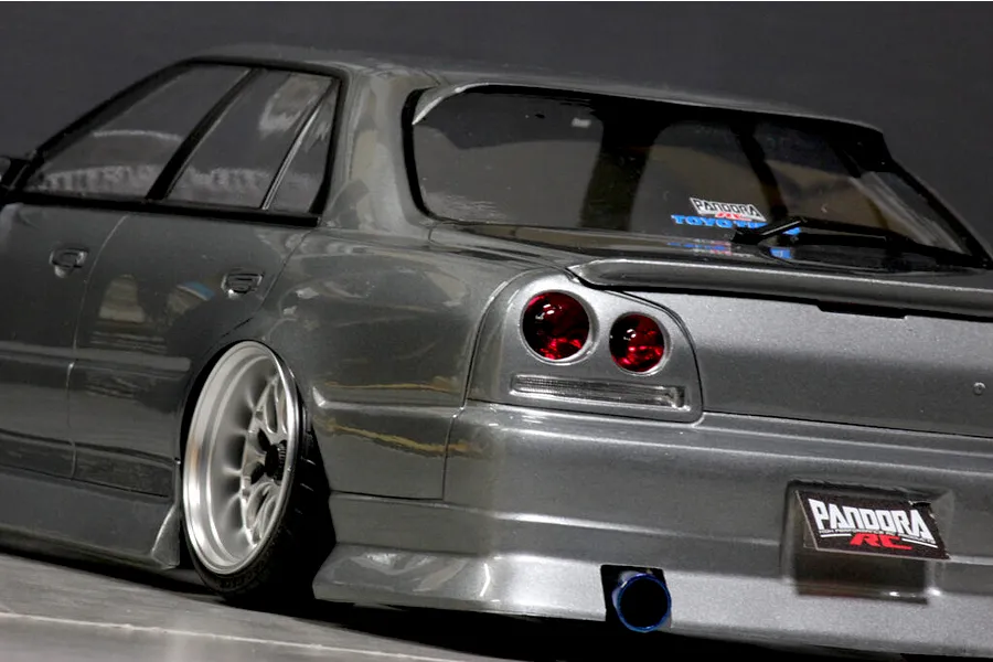 Close-up rear angled view of a grey ER34 Skyline RC drift car body showing custom deep dish wheels, exhaust, and Pandora RC decals.