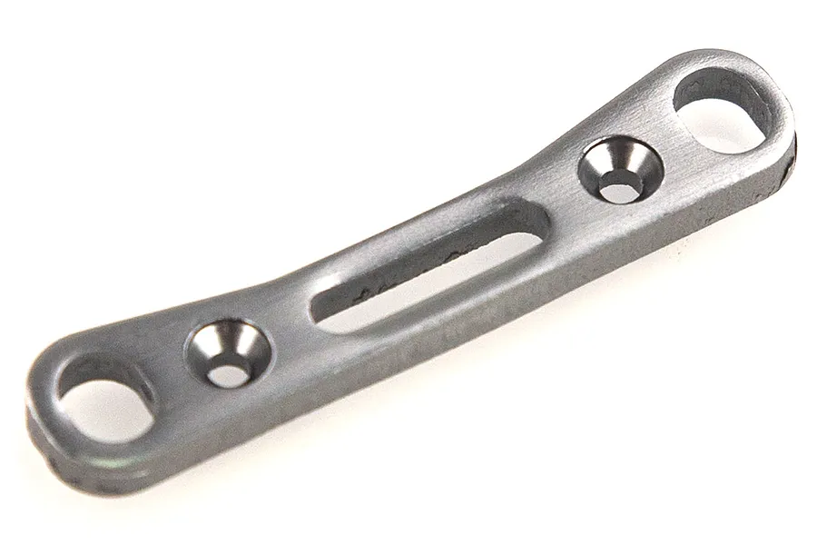 A gunmetal grey aluminium suspension arm pin mount for an RC car, featuring a curved design with two mounting holes and a central slot.