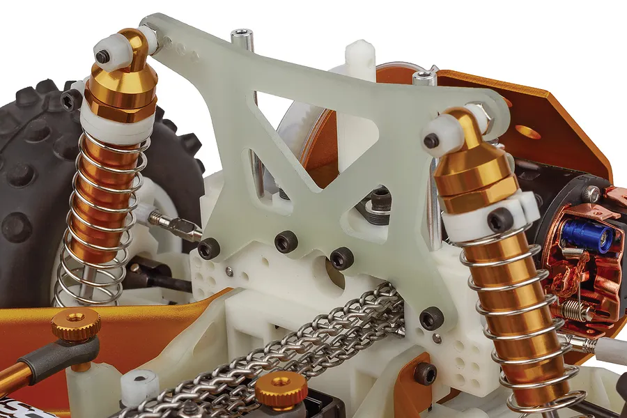 Close-up studio shot of the rear suspension and chain drive mechanism of a Team Associated RC10 RC buggy.