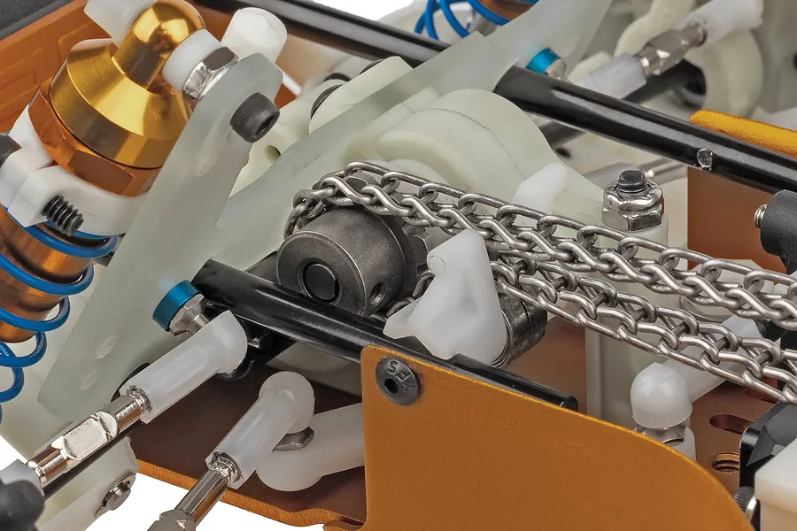 Close-up studio view of the chain drive system and suspension components on the Team Associated RC10 buggy kit.